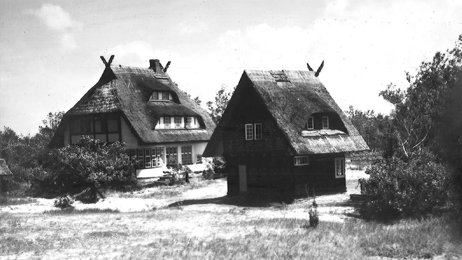 Haus Windhook und ein reetgedecktes Nebengebäude in der Dünenlandschaft – historische Schwarz-Weiß-Fotografie